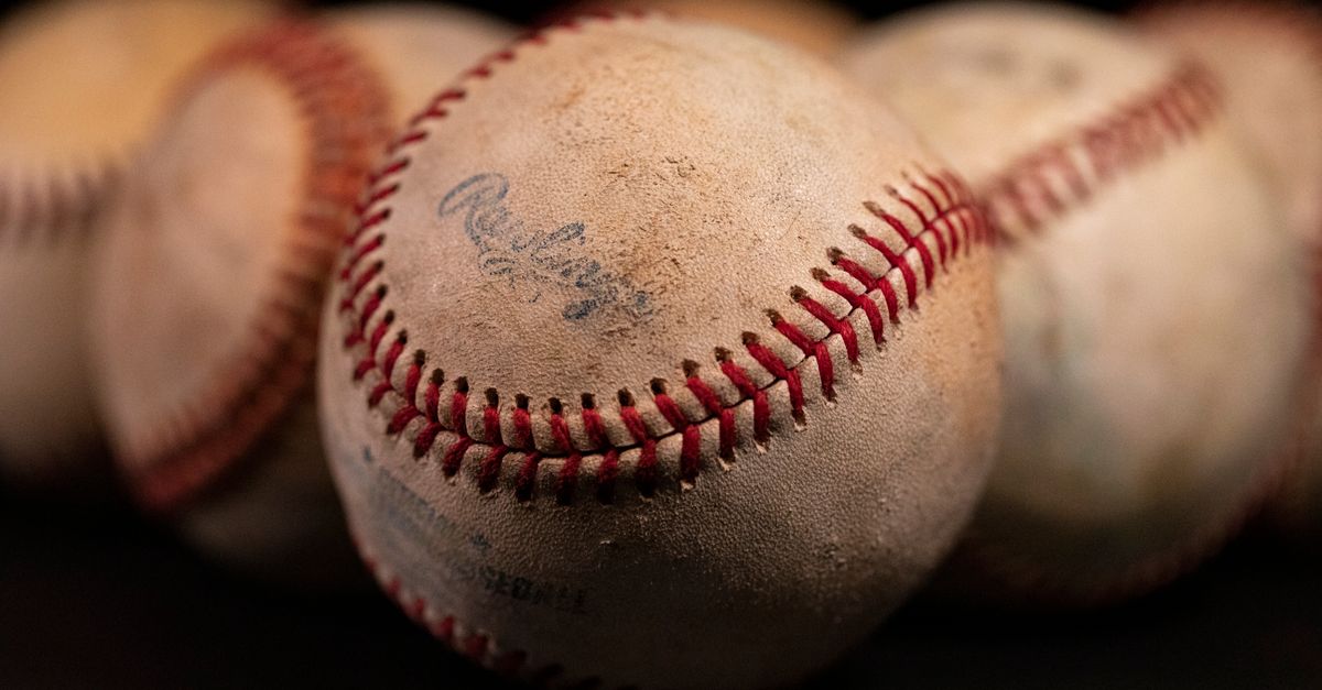 Focused close-up of old baseballs with visible stitching and texture against a dark background.